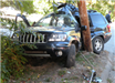 side of black car crashed into wooden pole