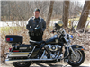 A police officer standing with a police motorcycle.